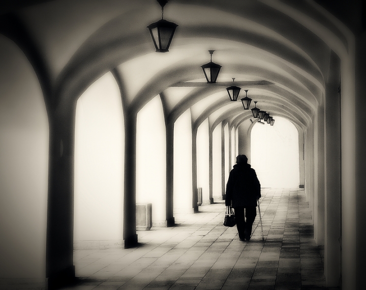 elderly woman walking in colonnade 